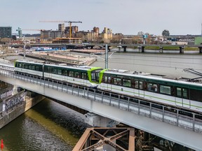 A REM train on an elevated track with the skyline in the background