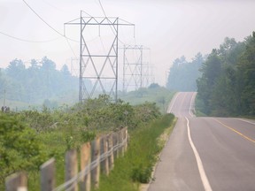 Smoke from forest fires in Ontario and Quebec is visible over hydro lines along Highway 506 near Fernleigh, about 160 kilometres west of Ottawa, June 6, 2023.