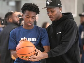 Bennedict Mathurin speaks with a student holding a basketball
