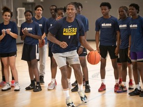 Bennedict Mathurin dribbles on court with students looking on