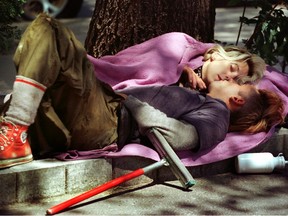 A couple sleep next to each other with a squeegee by their side in partial shade.