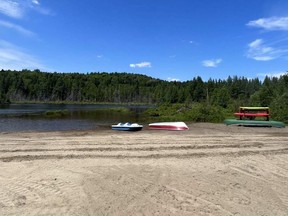 a sandy beach with canoes and a pedal boat