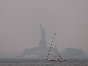 sailboat in the foreground, statue of liberty covered in haze in background