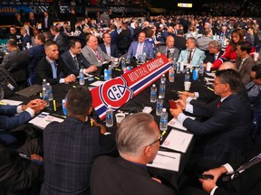 Men in suits surround a table with a 'Montreal Canadiens' sign on it in a large arena