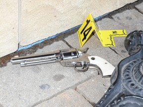 A silver revolver sits on the ground with a police evidence marker next to it