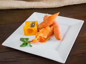 Peeled carrots with sharpener on wood