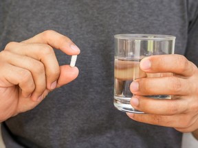 Man holding a pill and a glass of water