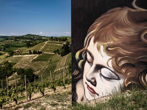 a mural of a woman's face overlooks italian fields of grapes