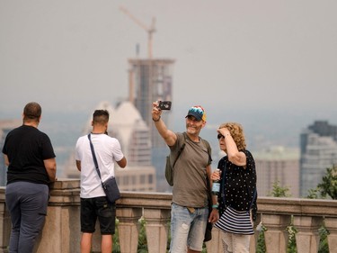a couple takes a selfie with the hazy montreal skyline behind them