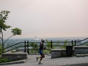 a jogger in the foreground with pink smoggy skies over montreal