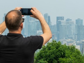 a man takes a photo of the smoggy montreal skyline