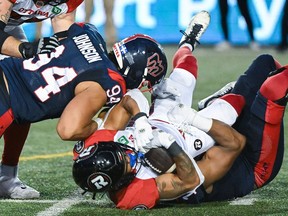 An Ottawa Redblacks player is tackled by two Montreal Alouettes defenders