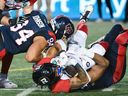Ottawa Redblacks' Devonte Williams, centre, is brought down by Montreal Alouettes' Mustafa Johnson (94) and Nick Usher during second half CFL football action in Montreal, Saturday, June 10, 2023.