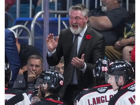 Patrick Roy speaks to players behind the bench