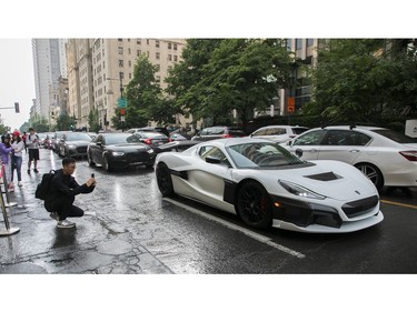 A man takes a photo of a passing vehicle outside the Grand Prix Party 2023 at the Ritz Carlton on Friday, June 16, 2023.