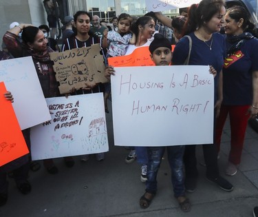 A boy holds a "housing is a basic human right!" sign at a protest