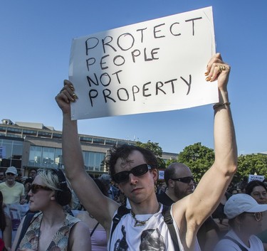 A protester holds up a sign that reads "protect people not property"