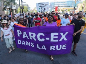People march in the street behind a large banner reading 'PARC-EX DANS LA RUE'