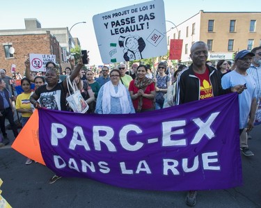A group of people marching in the street holds a purple sign that reads "Parc-Ex dans la rue"