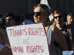 A woman holds a "tenants rights are human rights" sign at a protest