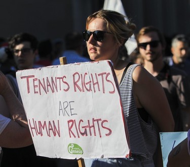 A woman holds a "tenants rights are human rights" sign at a protest