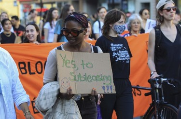 A woman holds a "Yes, to subleasing!!!" sign during a march