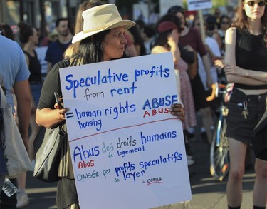 A woman holds a sign that says "Speculative profits from rents = human rights abuse" during a march