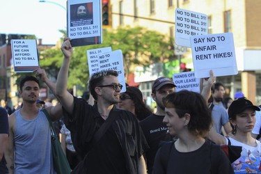 Protesters hold signs that read "Say no to unfair rent hikes" at a march