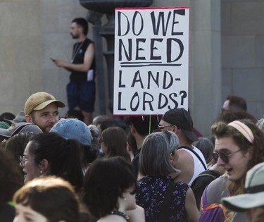 A sign that reads "Do we need landlords?" is held in the air during a protest