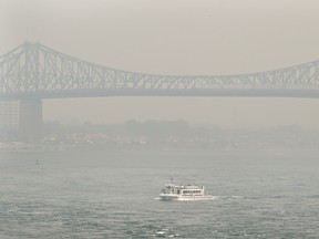 A boat passes by Jacques-Cartier Bridge obscured by a haze of smoke in Montreal on Sunday, June 25, 2023, as a smog warning is in effect for the city because of forest fires.
