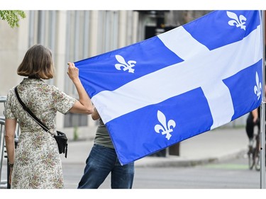 A woman poses next to a Quebec flag on Saint-Jean-Baptiste day in Montreal on Saturday, June 24, 2023.