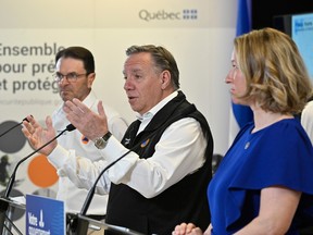 François Legault and two ministers speak at a news conference