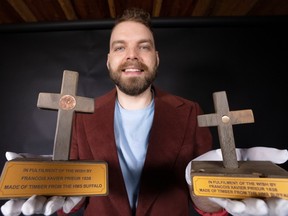 A photo of a man holding a wooden cross in each of his hands