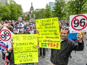 People hold signs at a protest against Bill 96
