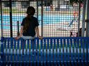 On the outside looking in, a young child sees the Hampstead pool through a steel fence at Hampstead Park on Monday July 3, 2023. Higher fees are in effect this year for residents and non-residents.
