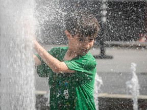 a young boy in a green shirt plays in a water fountain