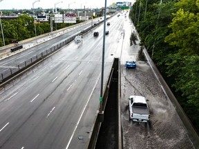 An aerial view shows cars driving through a shallow flood on a highway on-ramp