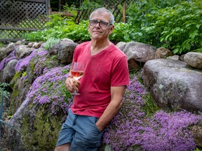 Longtime Montreal Gazette wine writer Bill Zacharkiw is seen with a glass of white in the garden of his home in the Laurentians on June 28, 2023.