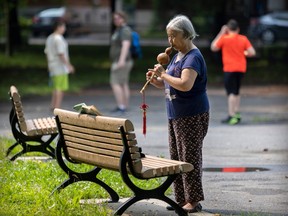 a woman plays a hulusi with her music resting on a park bench