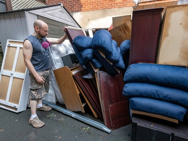 a man piles waterlogged furniture in his driveway