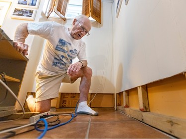 a senior checks for water damage on the walls of his home