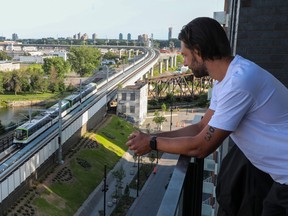 Drew Kuzminski leans over a balcony railing looking at a passing train