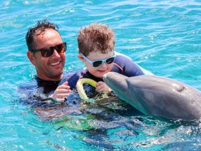 a man and child with special needs swim with a dolphin