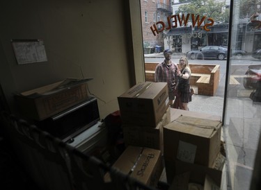 People look through the window at boxes inside a closed store