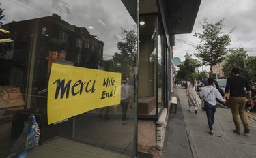 A sign taped in the window of a store says "Merci Mile End!"