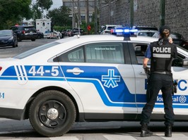 a montreal police officer stands next to a police vehicle