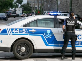 a montreal police officer stands next to a police vehicle