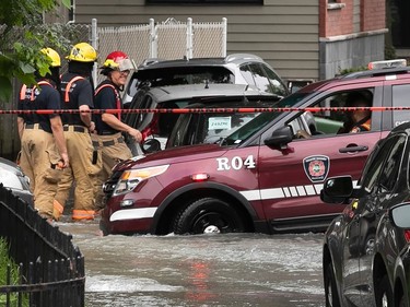 a firefighter in a partially submerged vehicle on a flooded street