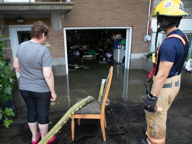 Montreal firefighter helps a local resident of Belair St. to pump out her flooded basement following main water break in St-Michel on Friday, July 28, 2023.