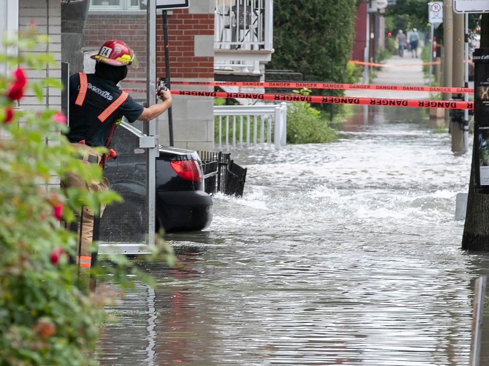 a firefighter photographs rising water after water main break